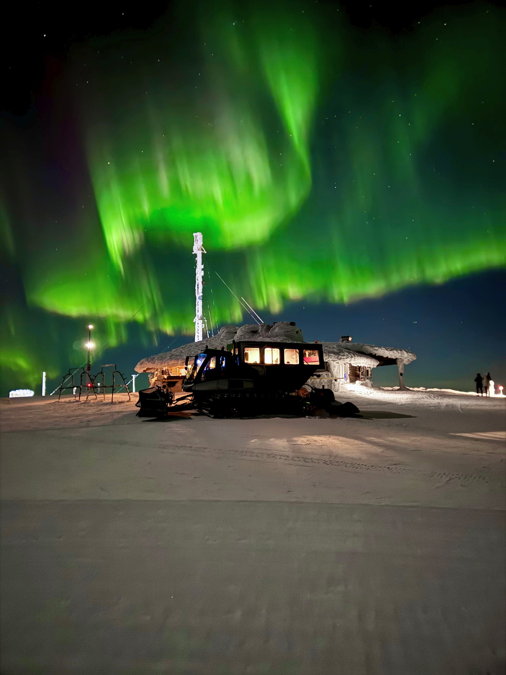 Norhtern lights dancing above restaurant Ylläskammi and snowcat