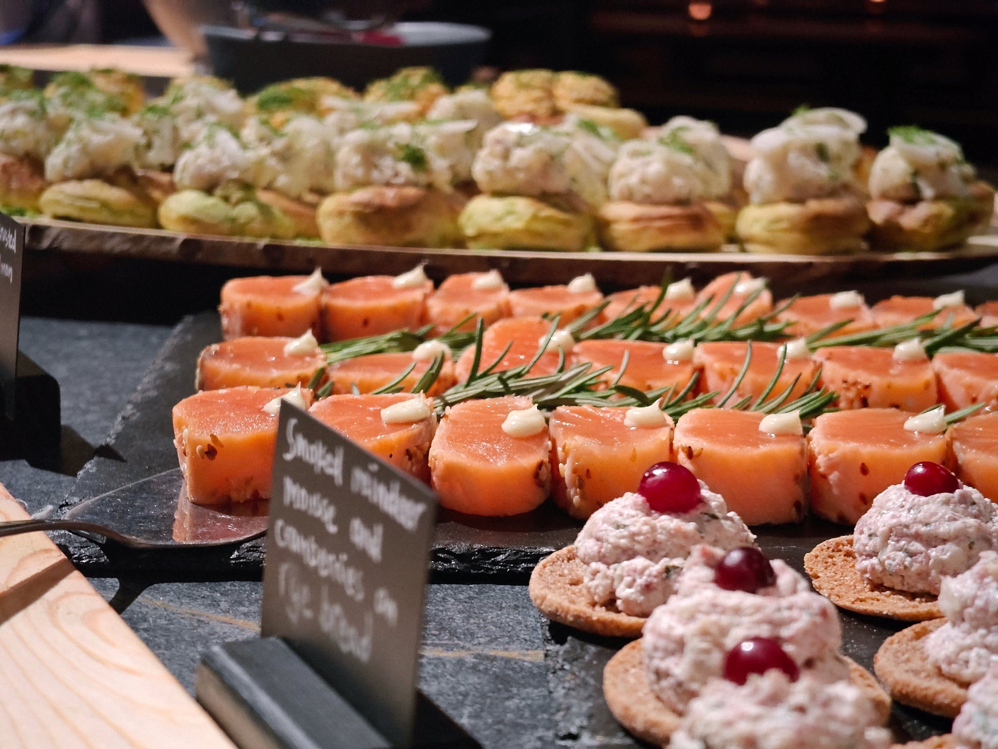 Salmon-sesam pastrami, smoked reindeer mousse and cranberry on rye bread and other appetizers served on buffet table