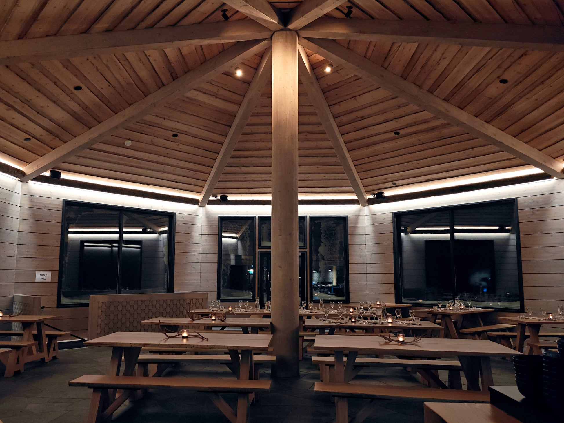 Dining room with with log walls, large windows and high ceiling