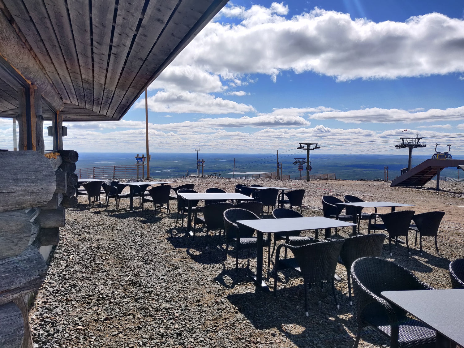 Sun is shining on summerday, tables are on outdoor teracce of Ylläskammi and you can see easily the scenery from the tables.