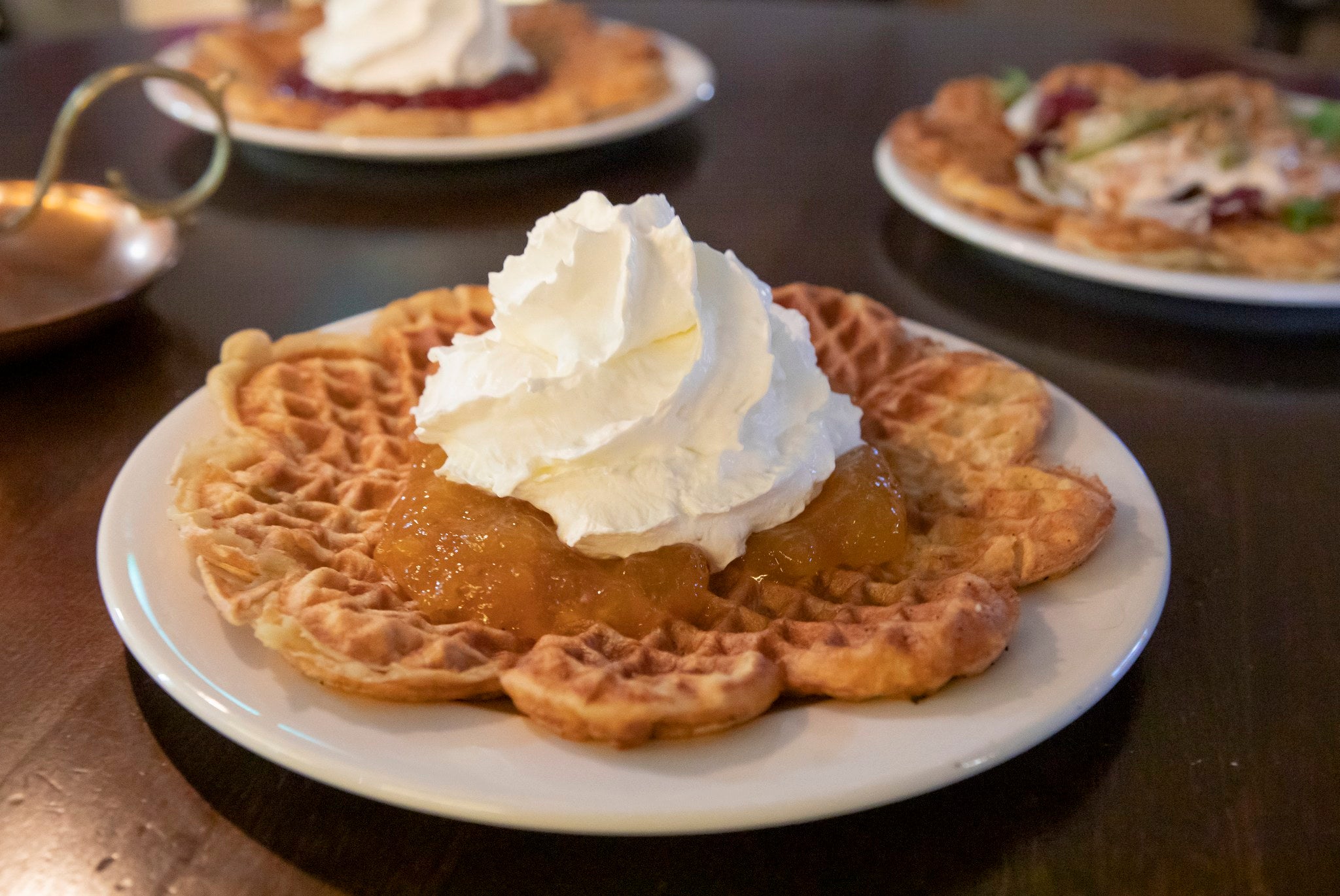 Delicious waffle with cloudberry jam and cream on the plate. 